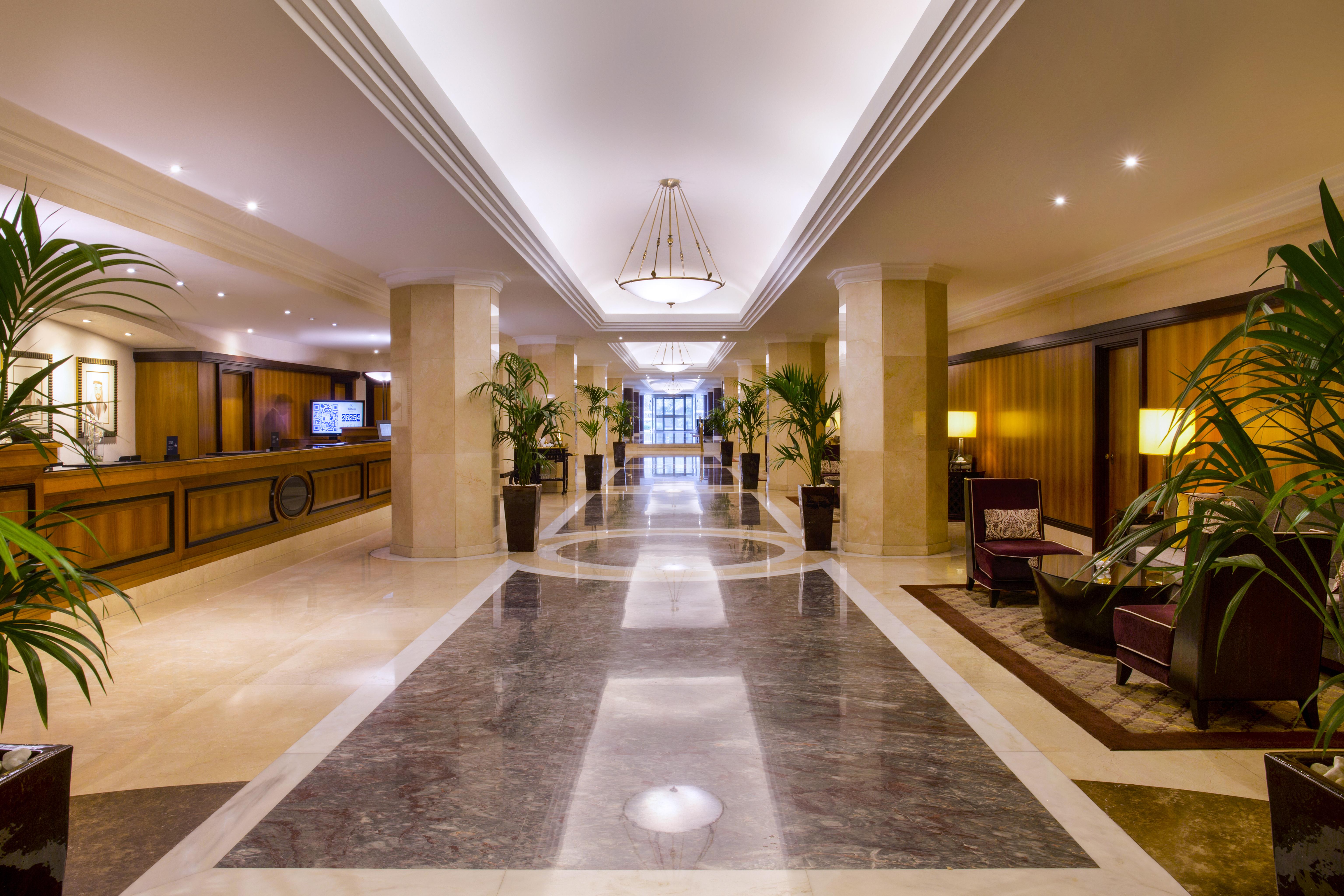 Radisson Blu Hotel & Resort, Abu Dhabi Corniche Exterior photo The photo displays an elegant hotel lobby. It features a spacious hallway with polished marble flooring and decorative lighting. On either side of the corridor are tall potted plants, adding a touch of greenery to the space. The reception desk is vis